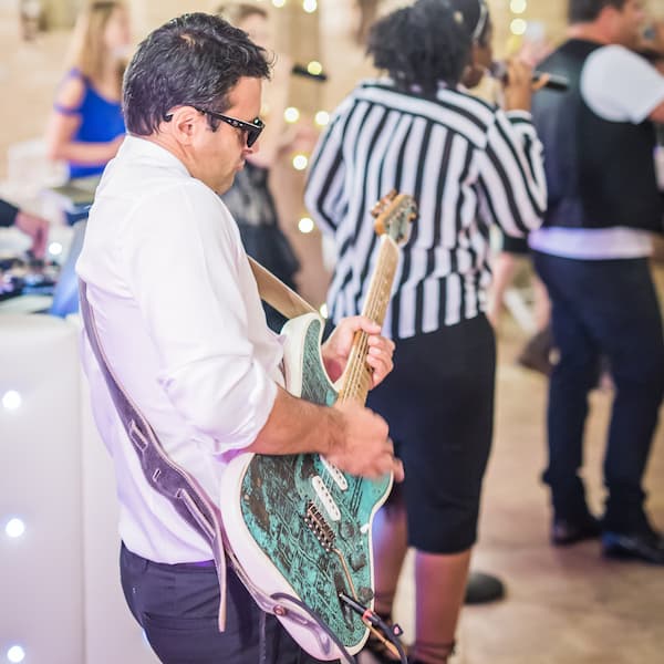 Le groupe de musique ROCK'ELLE se détend en extérieur, avec des membres jouant de la guitare et de la basse et la chanteuse s'amusant avec le micro.